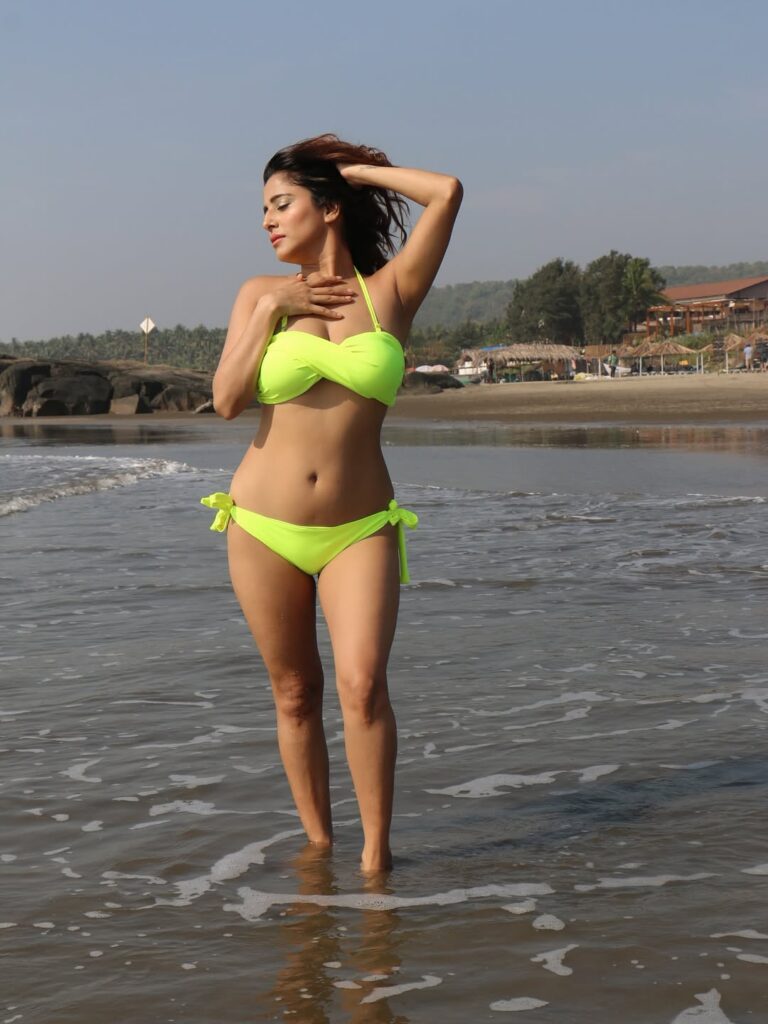 alt="Kate Sharma in a neon yellow bikini posing on Goa beach during a 2023 throwback photoshoot"